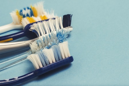 Several different used toothbrushes on a blue background. Toothbrush change concept, oral hygiene, big and friendly family, toothbrush selectionの写真素材