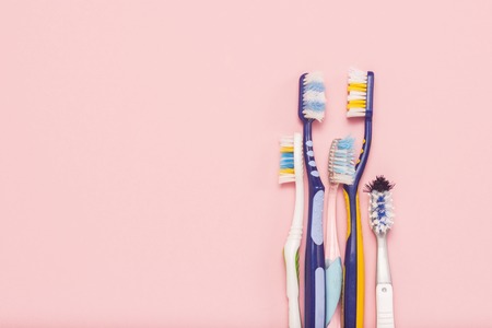 Several different used toothbrushes on a pink background. Toothbrush change concept, oral hygiene, big and friendly family, toothbrush selection. Flat lay, top viewの写真素材