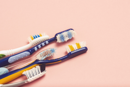 Several different used toothbrushes on a pink background. Toothbrush change concept, oral hygiene, big and friendly family, toothbrush selection. Flat lay, top viewの写真素材
