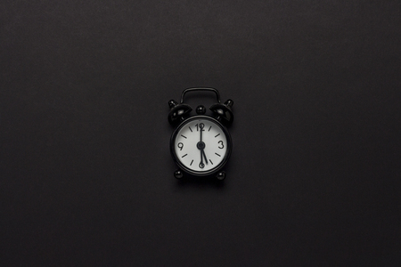 Black alarm clock on a black background. Concept day and night, time management, planning, schedule of day and night, minimalism. Flat lay, top viewの写真素材
