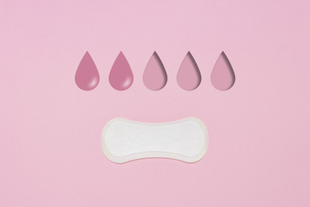 Feminine hygiene pad on a pink background. Concept of feminine hygiene during menstruation. Added drop mark, absorption level. two drops. Flat lay, top viewの写真素材