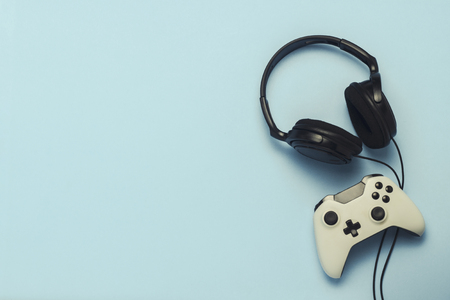 Headphones and gamepad on a blue background. . Concept of computer games, entertainment, gaming,...