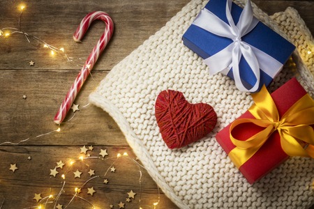 Heart of fabric, knitted scarf, gift boxes, luminous garland on a wooden background. The concept of lovers, Valentine's Day, a gift for a loved one. Flat lay, top viewの写真素材