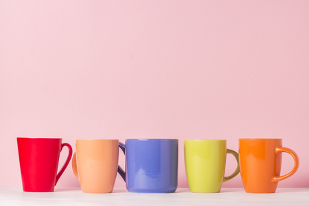 A lot of multicolored cups of coffee or tea on a pink background. The concept of a friendly company, a large family, meeting friends for a cup of tea or coffeeの写真素材
