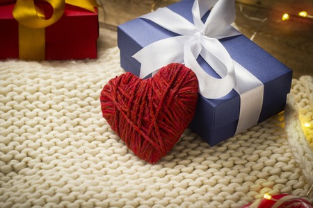 Heart of fabric, knitted scarf, gift boxes, luminous garland on a wooden background. The concept of...