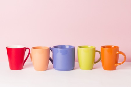 A lot of multicolored cups of coffee or tea on a pink background. The concept of a friendly company, a large family, meeting friends for a cup of tea or coffeeの写真素材