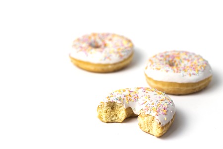 Bitten fresh tasty donut on a white background. Bakery concept, fresh pastries, delicious breakfastの写真素材
