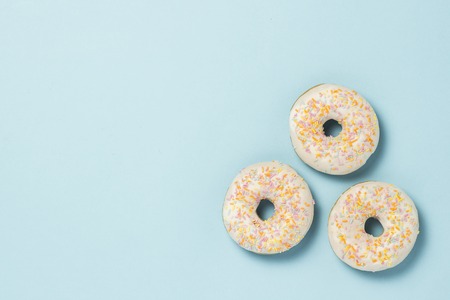 Three fresh delicious sweet donuts on a blue background. Fast food concept, bakery, breakfast,. Minimalism. Flat lay, top viewの写真素材