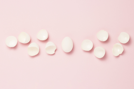 White egg and broken eggs around it on a pink background. The concept of life insurance, health and...