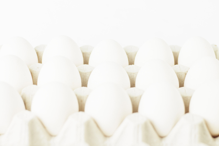 White chicken eggs in a paper tray on white background