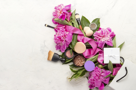 Gift white package, gift wrapped, decorative cosmetics, pink ribbon and pink peonies on a light background. Top Viewの写真素材