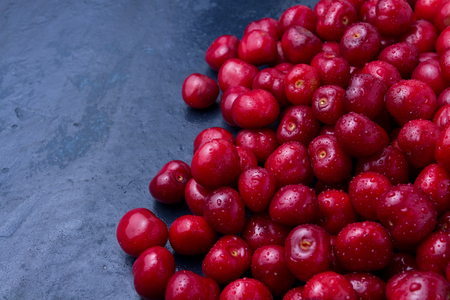 Freshly picked cherries with drops of dew and water on a dark blue stone background. The concept of harvesting. Flat lay, top view.の写真素材