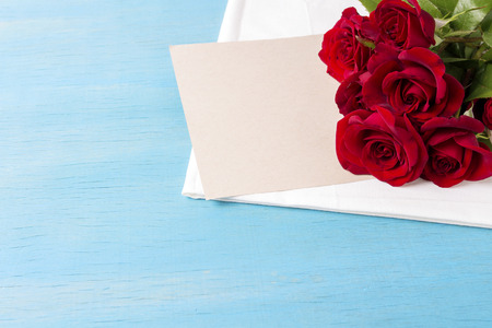 Bouquet of red roses, clean sheet, blue wood background. Copy space. Romantic gift for Valentine's Day holiday.の写真素材