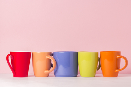 A lot of multicolored cups of coffee or tea on a pink background. The concept of a friendly company, a large family, meeting friends for a cup of tea or coffeeの写真素材