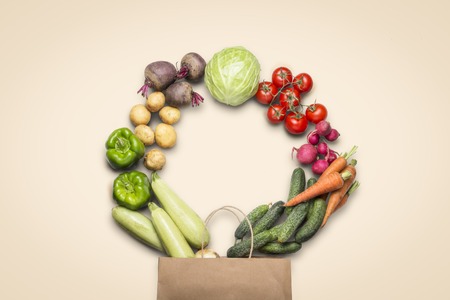 Paper shopping bag and fresh organic vegetables on a light background. Concept of buying farm...