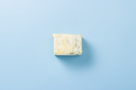 A piece of blue cheese on a blue background. Minimalism. Flat lay, top viewの写真素材