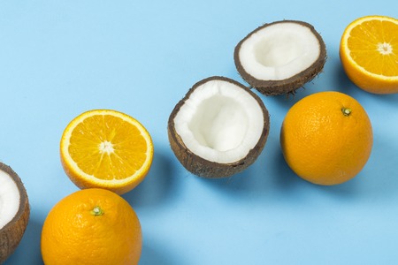 Cut orange and coconut on a blue background. Concept of tropical fruits, vacation and travel, diet and weight lossの写真素材