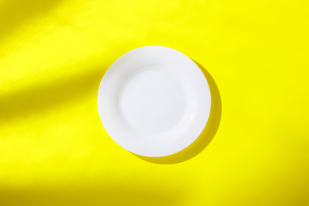 Empty white plate and on yellow background. The concept of losing weight, diet, choice, breakfast and lunch, hotel, tropic. Flat lay, Top viewの写真素材