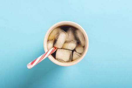 Refreshing iced coffee in a glass on a blue background. Concept summer, cola with ice, refreshing...