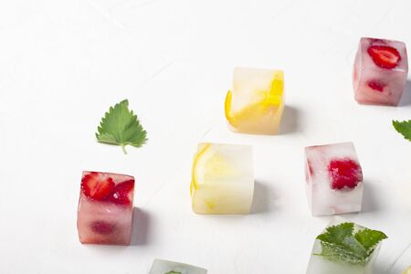 Ice cubes with fruit and mint leaves on a white stone background. Fruit ice concept, quenching...