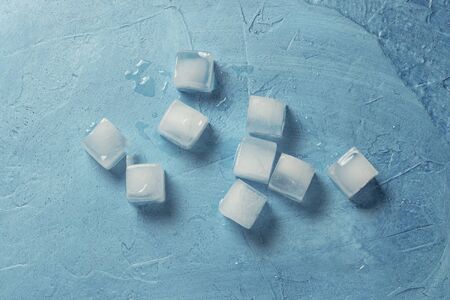 Ice cubes on a blue stone background. Shape of the square. Ice production concept. Flat lay, top...
