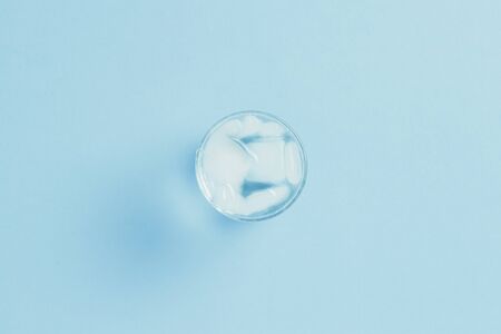 Refreshing cold Water with ice in a glass on a blue background. Concept of thirst, heat, refreshment in the summer. Flat lay, top view.の写真素材