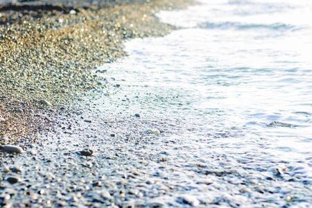 Sea surf on a pebbly beach at dawn or dusk. Seascape. Narrow focus.