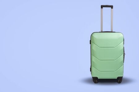 Light Green Suitcase on wheels on a light blue background. Travel concept, vacation trip, visit to relatives.の写真素材