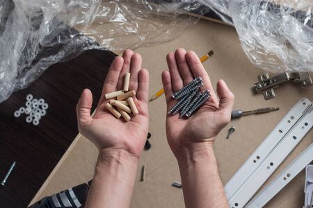 Hands of a man with a tool. Screwdriver, Screws, Furniture Details. Concept Workshop. Flat lay, top view.の写真素材