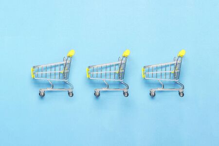 Three shopping trolley on a blue background. Concept of shopping, discount, sale. Flat lay, top...