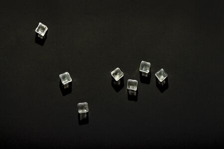 Ice cubes on a black background. The concept of heat, cooling. Natural light. Flat lay, top view.