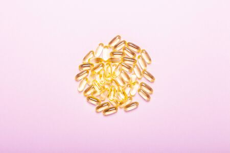 Capsules on a pink background. The concept of vitamins, fish oil, medicine, pharmaceuticals,...