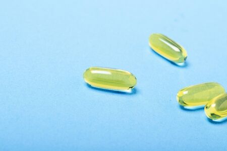 Capsules on a blue background. The concept of vitamins, fish oil, medicine, pharmaceuticals,...