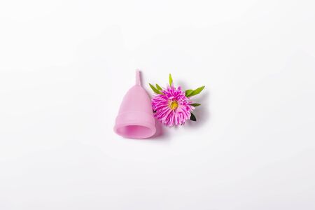 Pink menstrual cup and flower on a white background. Concept of menstruation, the choice between feminine hygiene products. Flat lay, top.の写真素材