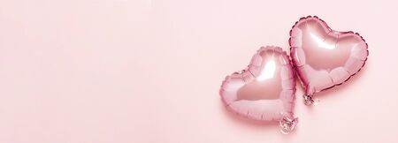 Two pink air balloons in the shape of a heart on a pink background. Concept Valentine's Day, Wedding Decoration. Foil balls. Banner. Flat lay, top view.の写真素材