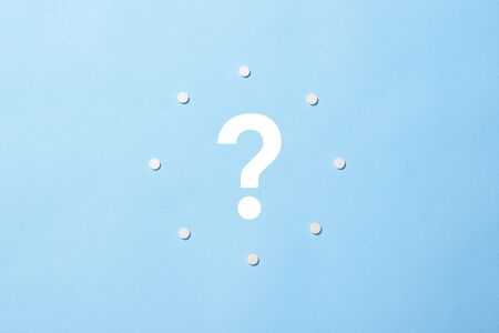 Clock with pills instead of numbers and a question mark on a blue background. Insomnia, taking pills according to the regimen, vitamins. Flat lay, top view.の写真素材