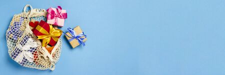Gifts in a fashionable bag for shopping on a blue background. Gift shopping concept, discount, sale. Banner. Flat lay, top view.の写真素材
