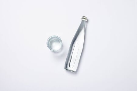 Bottle of pure crystal water and glass on a white background under sunlight. Banner. Concept of thirst, heat, summer, tropic. Flat lay, top view.の写真素材