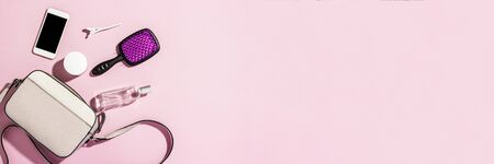 Women's QUILTED CROSSBODY BAG with a long handle and accessories, phone, comb, perfume, cream on a pink background. Banner. Concept of fashion and beauty, modern, stylish. Flat lay, top view.の写真素材