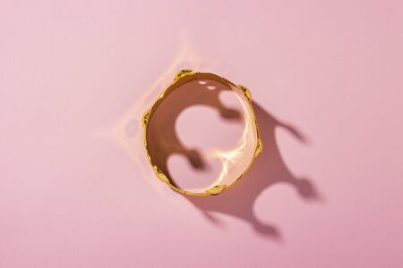 Gold crown on a pink background. Flat lay, top view.の写真素材