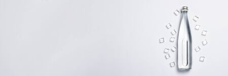 Bottle of pure crystal water with ice cubes on a white background under sunlight. Banner. Concept of thirst, heat, summer, tropic. Flat lay, top view.の写真素材