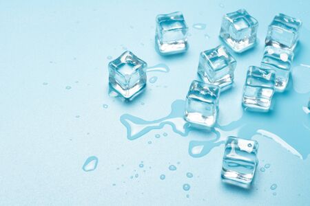 Ice cubes with water on a blue background. Ice concept for drinks. Banner. Flat lay, top view.