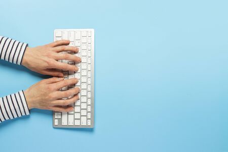 Female hands and keyboard on a blue background. Concept workspace, work at the computer, freelance, design. Banner. Flat lay, top view.の写真素材