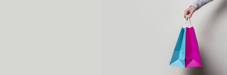 Female hand holds shopping bags on a white background. Concept shopping, discount, sale. Banner.の写真素材