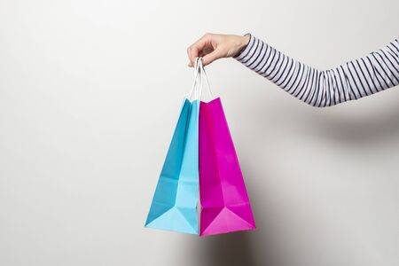 Female hand holds shopping bags on a white background. Concept shopping, discount, sale. Banner.の写真素材