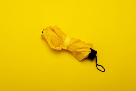 Yellow rain umbrella on an isolated yellow background. The concept of rain, autumn, protection, stylish, trendy. Banner. Flat lay, top view.の写真素材
