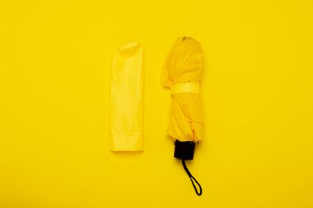Yellow rain umbrella and case on an isolated yellow background. The concept of rain, autumn, protection, stylish, trendy. Banner. Flat lay, top view.の写真素材