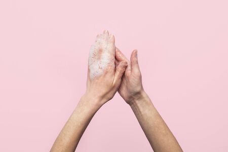 Hand washing. Soapy female hands on a pink background. Concept of the rules of washing and handling hands. Top view, flat lay.の写真素材