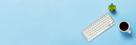 Keyboard, flower and cup with tea or coffee on a blue background. Concept workspace, work at the...