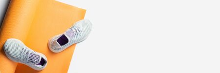 Yoga mat and sneakers on a white background. Sport and diet. Top view, flat lay. Banner.